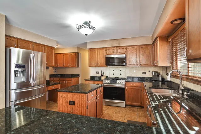 a kitchen with stainless steel appliances granite countertop a stove top oven a sink dishwasher a refrigerator and cabinets with wooden floor