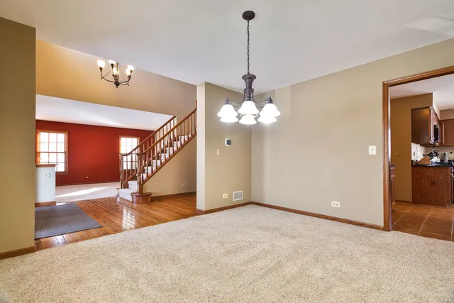 a view of a livingroom with a chandelier fan and wooden floor