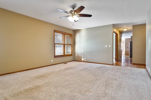 an empty room with windows and ceiling fan