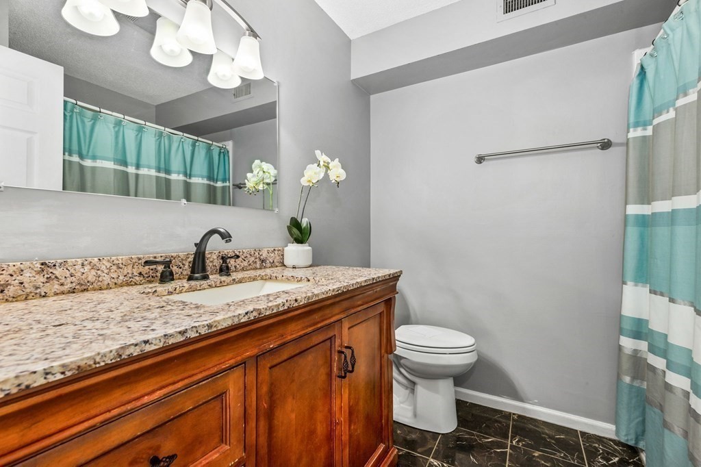 5 Beal's Cove Road, Unit B Hingham, MA 02043 - Photo 19 of 27 a bathroom with a granite countertop sink a toilet and a mirror