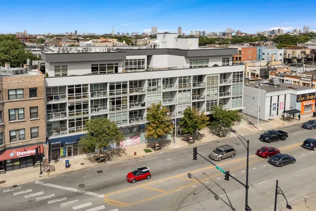 a view of a city that has tall buildings and cars parked