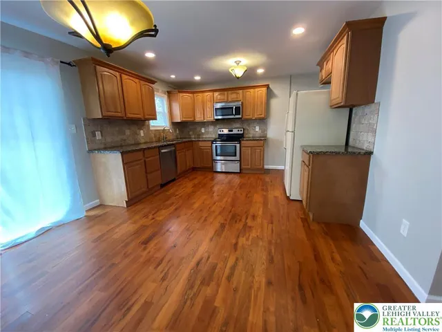 a kitchen with stainless steel appliances wooden floors and wooden cabinets