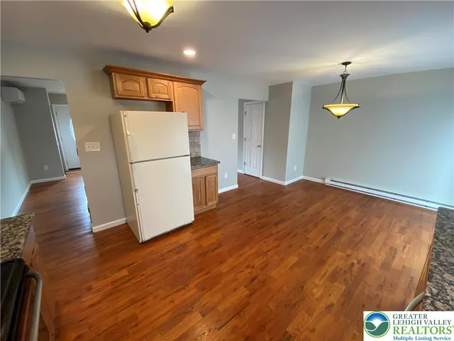 a view of a refrigerator in kitchen and an empty room