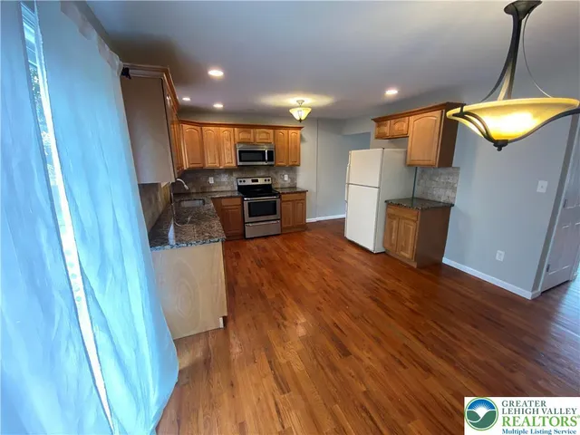 a kitchen with stainless steel appliances granite countertop a refrigerator a stove and a wooden floors