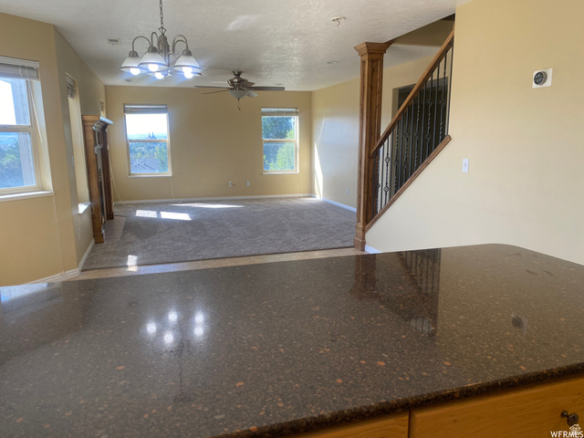 83 Canterbury Circle Logan, UT 84321 - Photo 10 of 23 Unfurnished living room featuring suspended lighting, a ceiling fan, and ornate columns