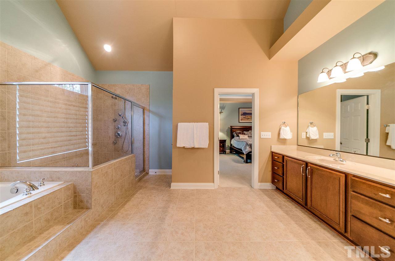 2408 Loring Court Raleigh, NC 27613 - Photo 11 of 25 a large en suite bathroom with a tub sink and mirror
