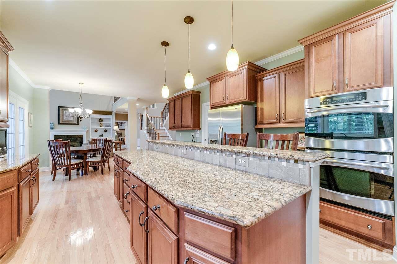 2408 Loring Court Raleigh, NC 27613 - Photo 5 of 25 a kitchen with stainless steel appliances granite countertop a stove top oven a sink dishwasher a dining table and chairs with wooden floor
