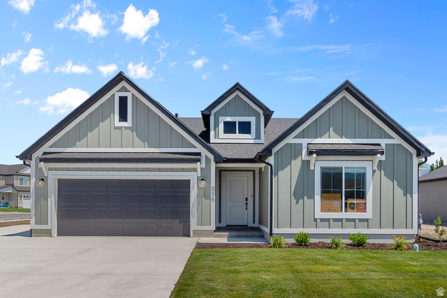 537 South Rivergate Drive Logan, UT 84321 - Photo 1 of 20 Exterior featuring sage green vertical siding, dark gray horizontal garage door, white trim, and a dormer window