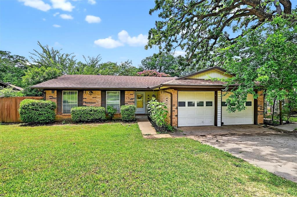 Ranch-style home featuring an attached garage, concrete driveway, brick siding, and a shingled roof