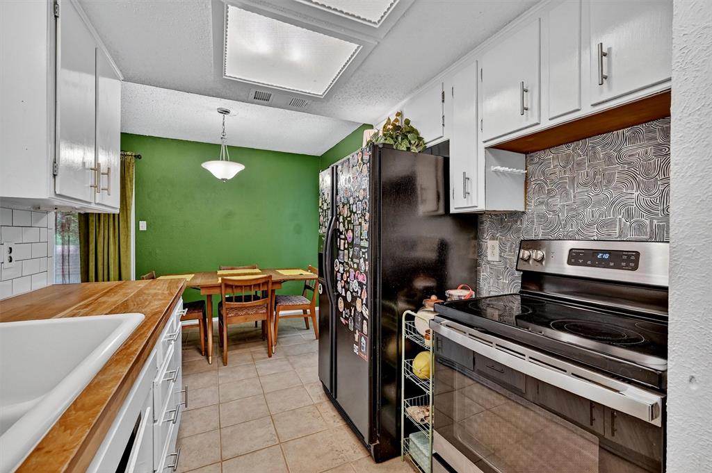 813 Glen Key Street Denison, TX 75020 - Photo 11 of 28 Kitchen with stainless steel electric stove, white cabinets, decorative backsplash, light tile patterned flooring, and hanging light fixtures