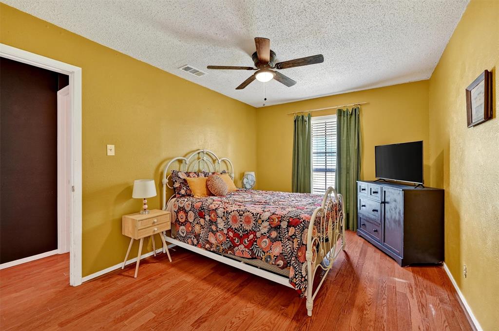 813 Glen Key Street Denison, TX 75020 - Photo 17 of 28 Bedroom with a textured ceiling, wood finished floors, a ceiling fan, and a textured wall