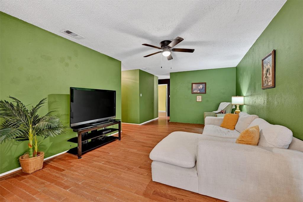 813 Glen Key Street Denison, TX 75020 - Photo 6 of 28 Living area with ceiling fan, wood finished floors, and a textured ceiling