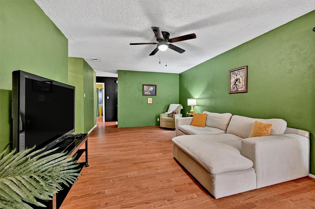 813 Glen Key Street Denison, TX 75020 - Photo 7 of 28 Living room featuring a ceiling fan, light wood finished floors, and a textured ceiling