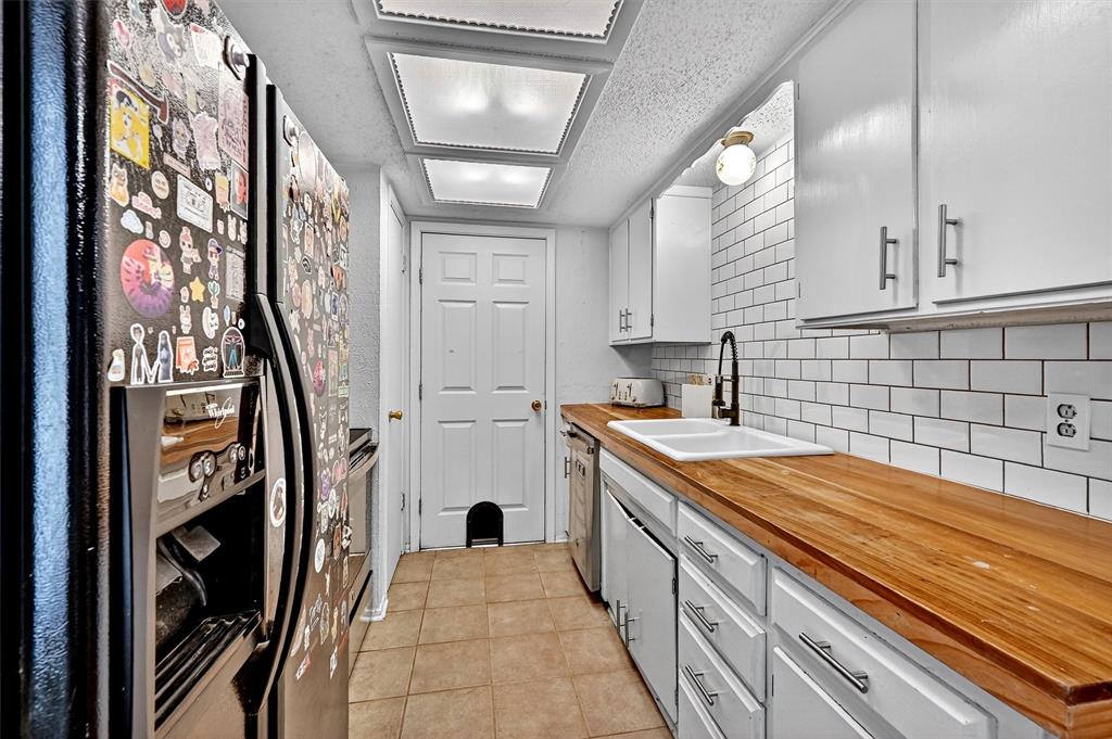 813 Glen Key Street Denison, TX 75020 - Photo 9 of 28 Kitchen featuring appliances with stainless steel finishes, wooden counters, decorative backsplash, light tile patterned flooring, and a textured ceiling