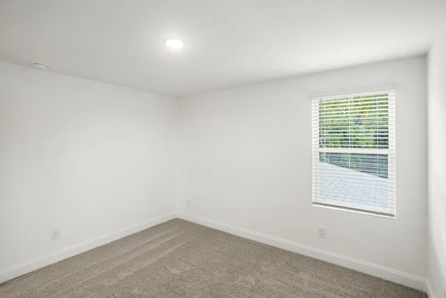 a view of a white house next to a yard and large trees