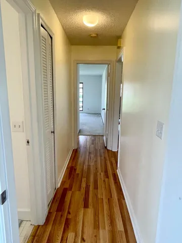 a view of a hallway with wooden floor and a bathroom