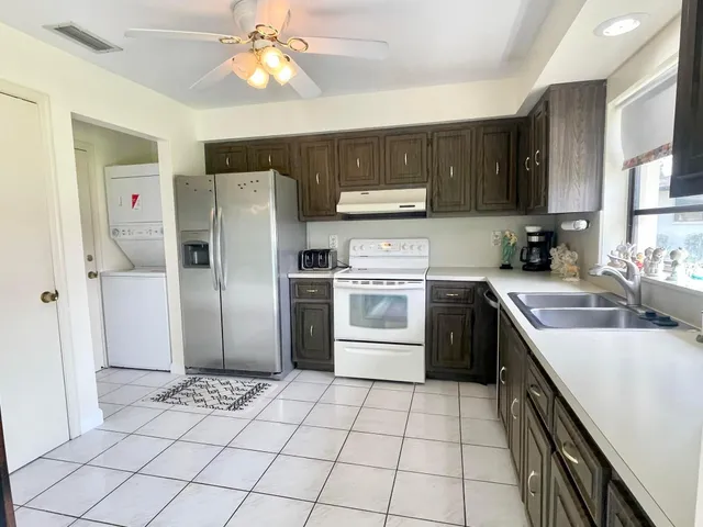 a kitchen with stainless steel appliances granite countertop a sink a stove a refrigerator cabinets a dining table and chairs