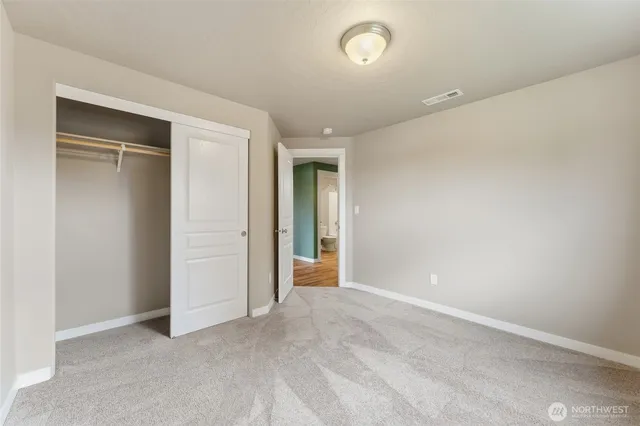 an empty room with closet and a hallway