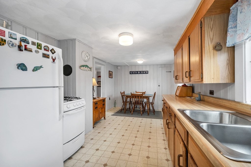 558 Winnacunnet Road Hampton, NH 03842 - Photo 18 of 40 a kitchen with granite countertop a sink a stove a refrigerator and a cabinets