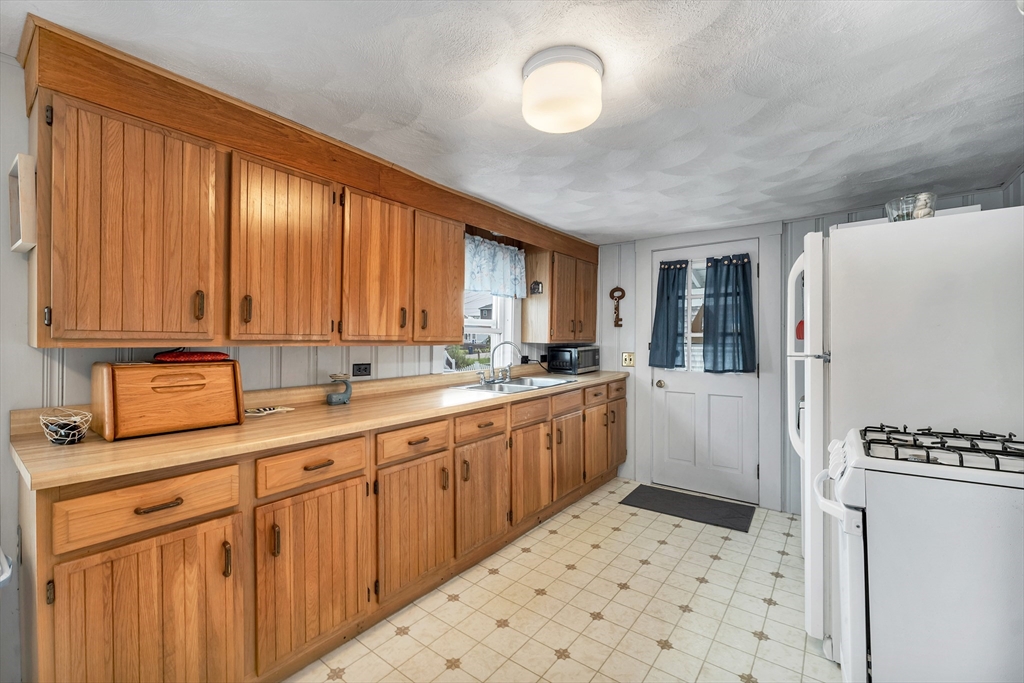 558 Winnacunnet Road Hampton, NH 03842 - Photo 20 of 40 a kitchen with a sink a refrigerator and cabinets