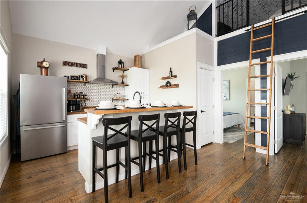 1053 Johnson Road Port Bolivar, TX 77617 - Photo 11 of 27 a kitchen with stainless steel appliances granite countertop a refrigerator a microwave a stove and a dining table with wooden floor