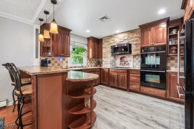 a kitchen with stainless steel appliances granite countertop a stove top oven a sink dishwasher a dining table and chairs with wooden floor