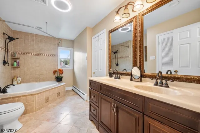 a spacious bathroom with a double vanity sink toilet mirror and bathtub