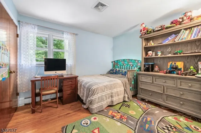 a bedroom with a bed a dresser and a flat screen tv