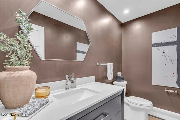 a bathroom with a granite countertop sink and a mirror with toilet