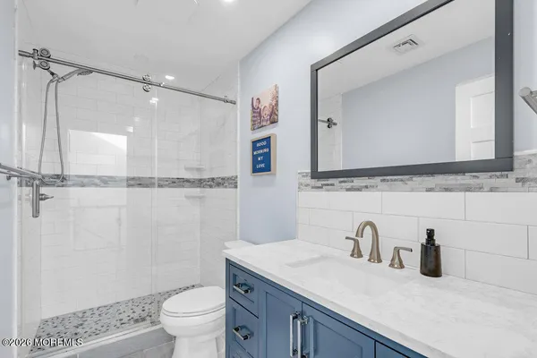 a bathroom with a granite countertop sink a toilet and a mirror