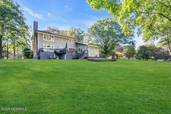 a view of a house with a big yard and large trees
