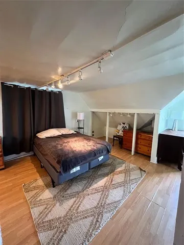 a spacious bedroom with a bed and wooden floor