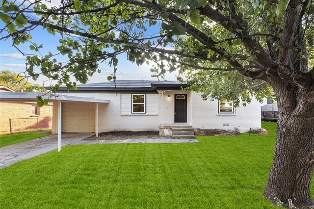 a view of a house with a yard and a large tree
