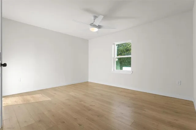 an empty room with a window and a ceiling fan