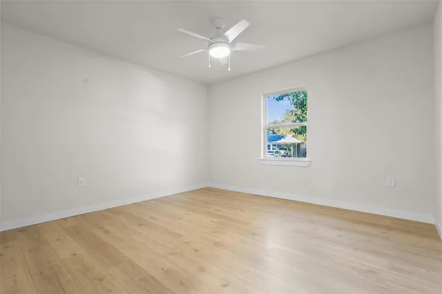 an empty room with a window and a ceiling fan
