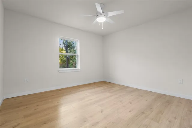 an empty room with a window and ceiling fan