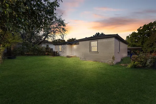 a backyard of a house with plants and large tree