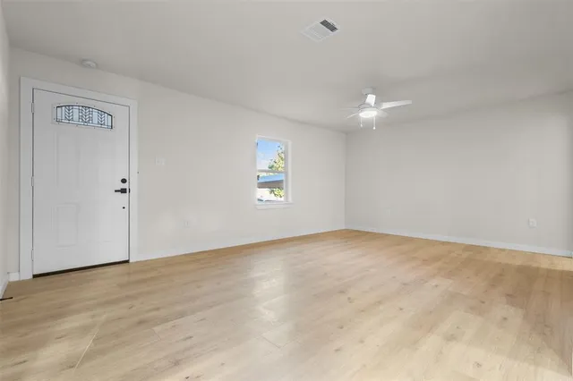 an empty room with windows and a ceiling fan
