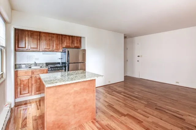 a kitchen with granite countertop a refrigerator and a stove top oven