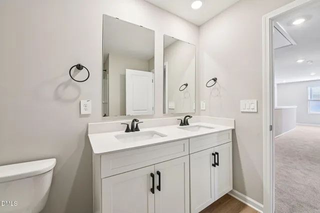 a bathroom with a toilet a sink a mirror a vanity and window