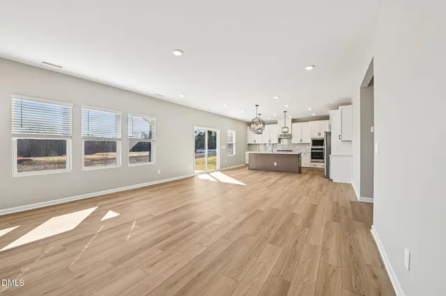 a view of a hallway with wooden floor and a bathroom