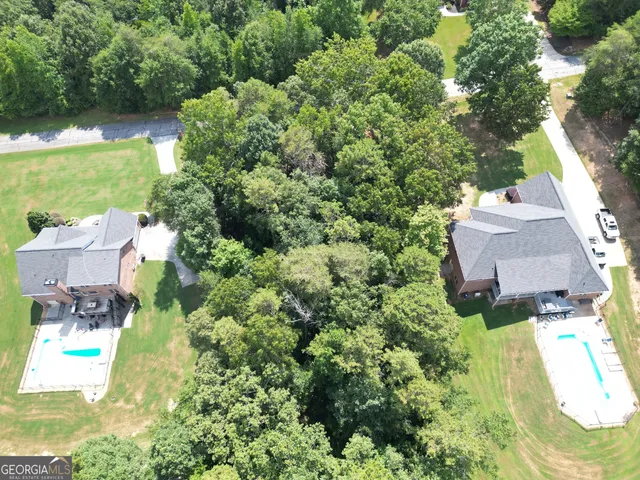 an aerial view of residential house with outdoor space and trees all around