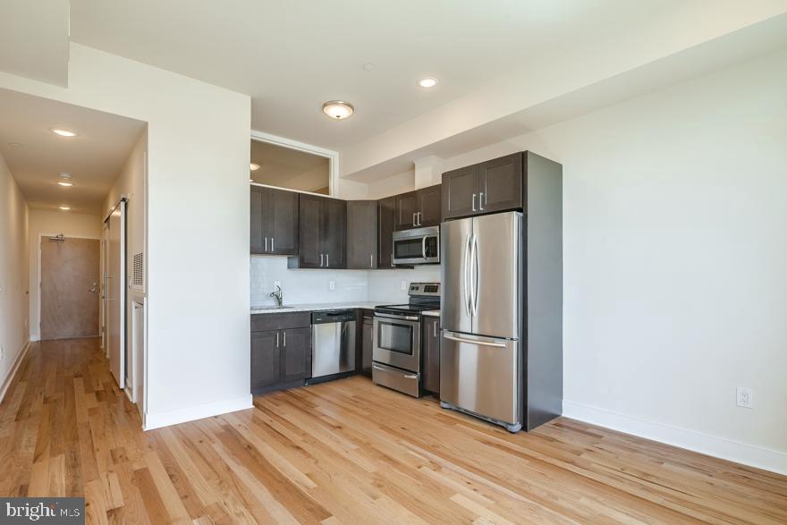 a kitchen with stainless steel appliances wooden floor and wooden cabinets