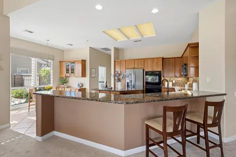 a kitchen with stainless steel appliances kitchen island granite countertop a table and chairs in it