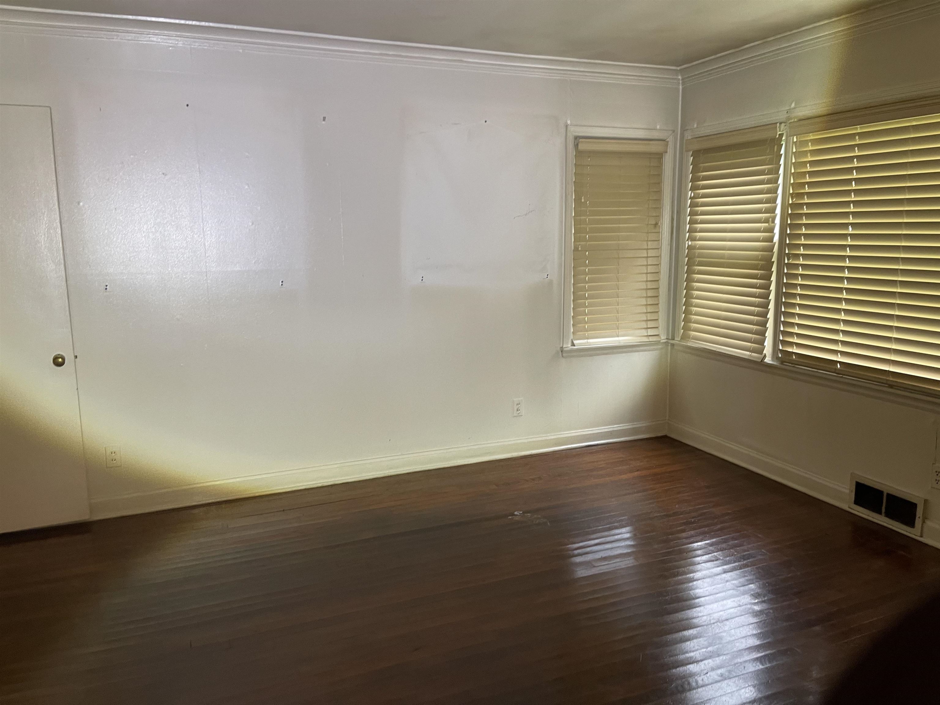895 Enfield Road Memphis, TN 38116 - Photo 2 of 9 a view of an empty room with wooden floor and a window