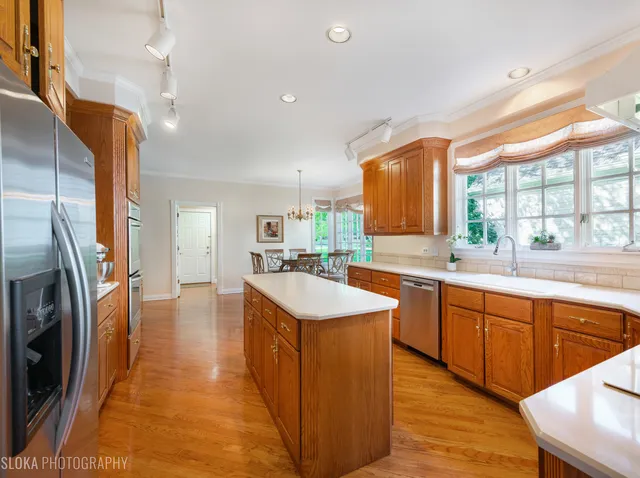 a large kitchen with stainless steel appliances granite countertop a sink a stove and a refrigerator