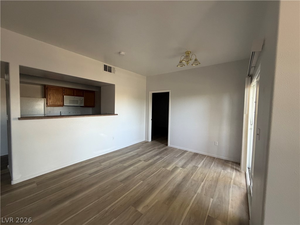 7255 West Sunset Road, Unit 1158 Las Vegas, NV 89113 - Photo 4 of 10 A well-lit living area features modern wood flooring and an open-concept kitchen pass-through.