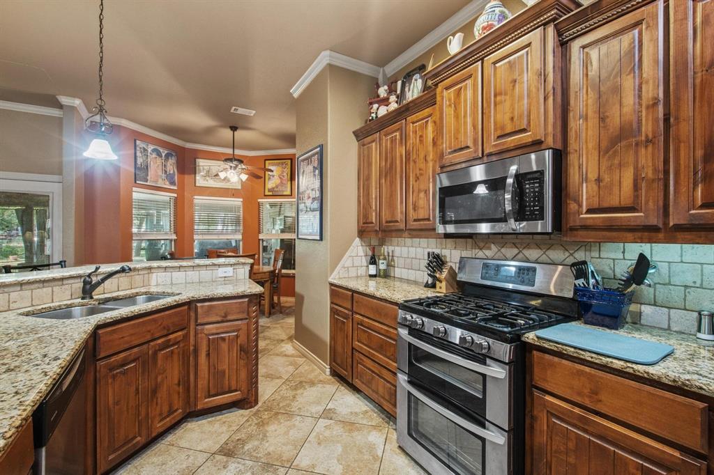 112 Knight Court Springtown, TX 76082 - Photo 11 of 26 Kitchen featuring wood cabinetry, granite countertops, stainless steel appliances, a tile backsplash, and tile flooring