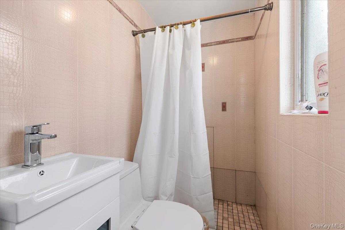 82-06 166th Street Queens, NY 11432 - Photo 11 of 25 Full bath featuring vanity, tile walls, and a shower with curtain