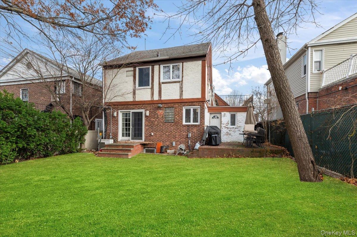 82-06 166th Street Queens, NY 11432 - Photo 18 of 25 Back of property featuring brick siding, a fenced backyard, stucco siding, and a patio